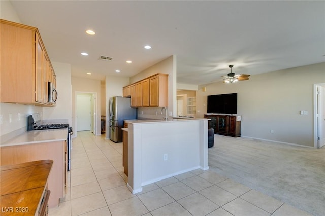 kitchen with ceiling fan, stainless steel appliances, light brown cabinetry, light colored carpet, and kitchen peninsula