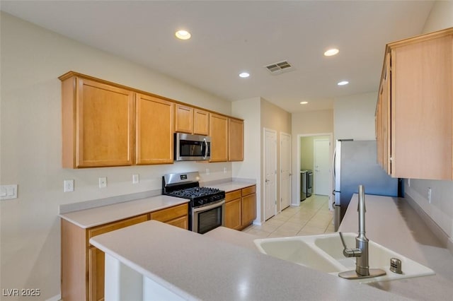 kitchen featuring light tile patterned flooring, sink, appliances with stainless steel finishes, kitchen peninsula, and independent washer and dryer