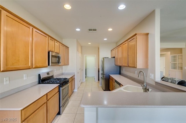 kitchen with sink, appliances with stainless steel finishes, light tile patterned flooring, light brown cabinetry, and kitchen peninsula