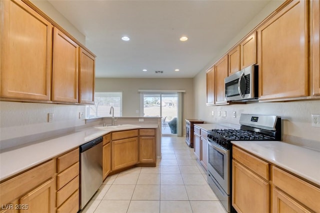 kitchen with sink, light tile patterned floors, light brown cabinets, and appliances with stainless steel finishes