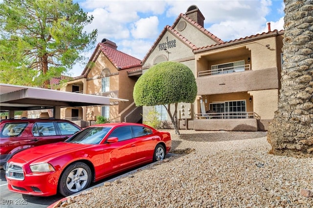 view of front of property with a tile roof, covered and uncovered parking, and stucco siding