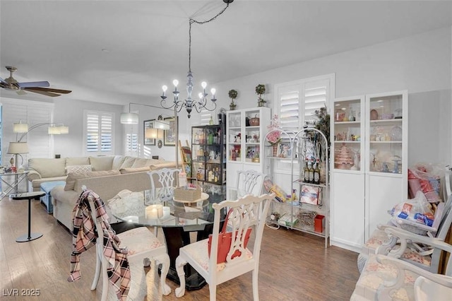 dining space featuring wood-type flooring and ceiling fan with notable chandelier