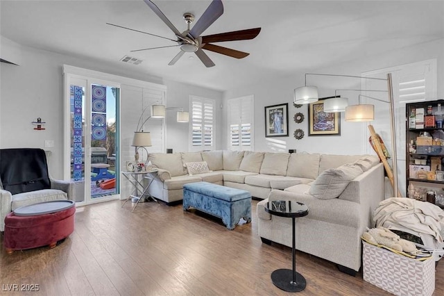 living room featuring dark wood-type flooring and ceiling fan