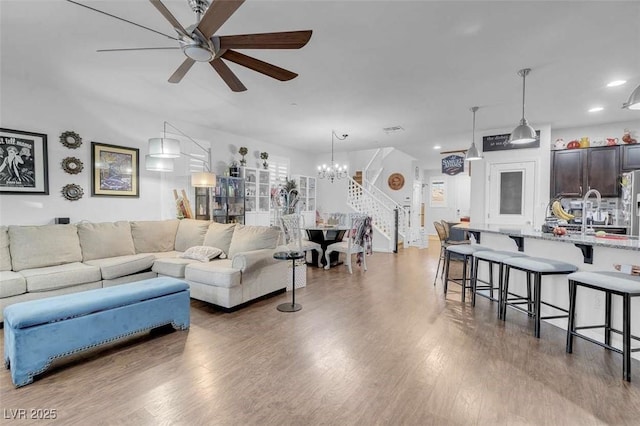 living room featuring sink, ceiling fan with notable chandelier, and wood-type flooring