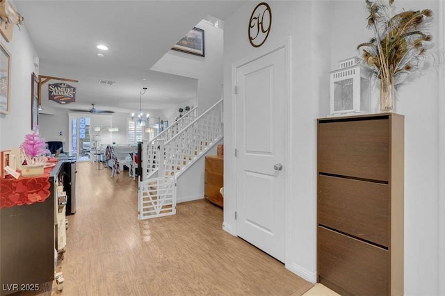 interior space with ceiling fan with notable chandelier and light hardwood / wood-style floors