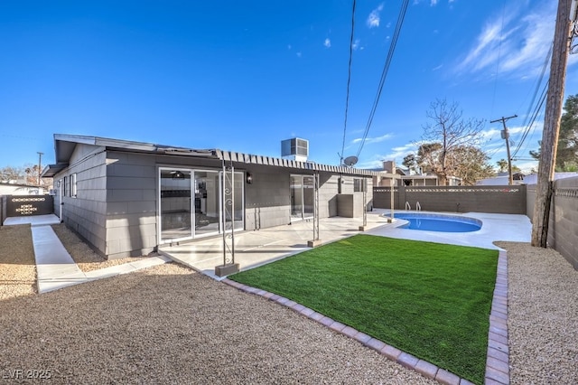 back of house with central AC unit, a fenced in pool, a patio area, and a lawn