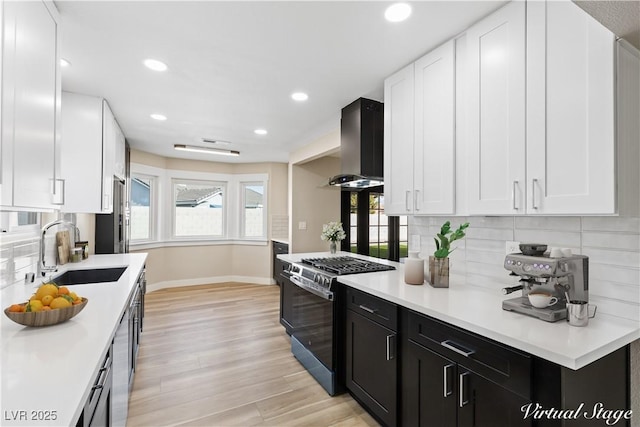 kitchen featuring ventilation hood, stainless steel range with gas cooktop, sink, and decorative backsplash