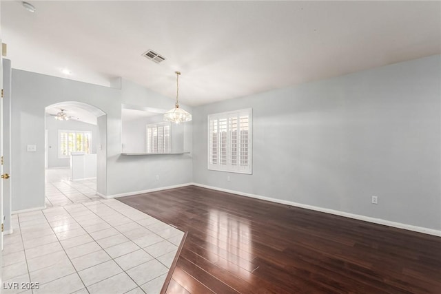 empty room featuring lofted ceiling, a notable chandelier, and light hardwood / wood-style flooring