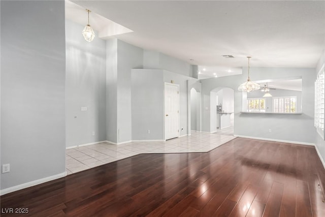 unfurnished living room featuring vaulted ceiling, a notable chandelier, and light wood-type flooring