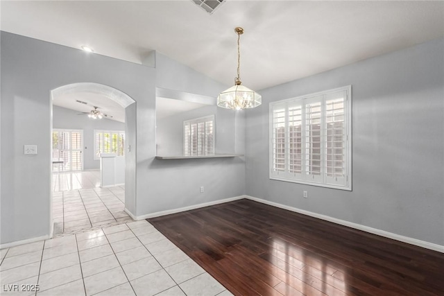 unfurnished room with lofted ceiling, ceiling fan with notable chandelier, and light wood-type flooring