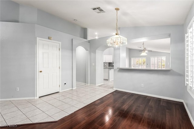 spare room with lofted ceiling, ceiling fan with notable chandelier, and light hardwood / wood-style flooring