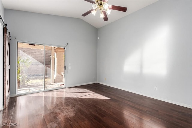 empty room featuring dark hardwood / wood-style floors, ceiling fan, a barn door, and vaulted ceiling