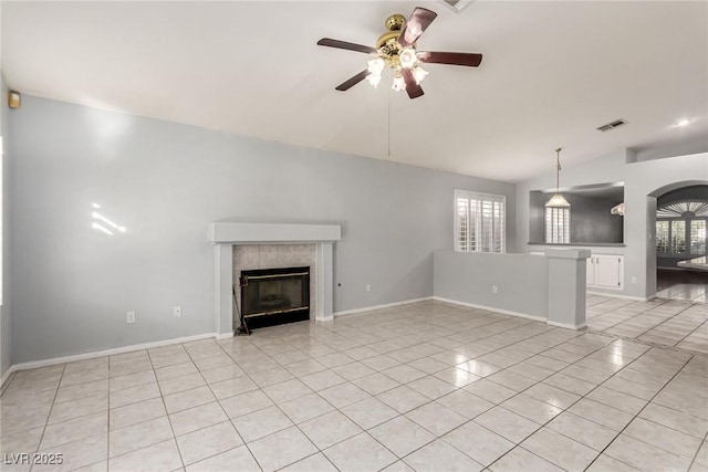 unfurnished living room with a tiled fireplace, lofted ceiling, light tile patterned floors, and ceiling fan