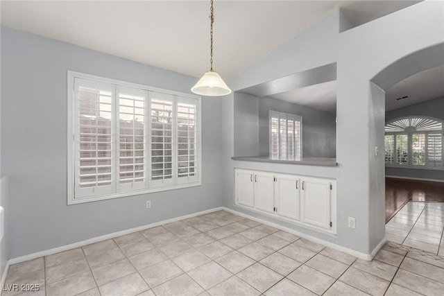 unfurnished dining area with light tile patterned floors and vaulted ceiling