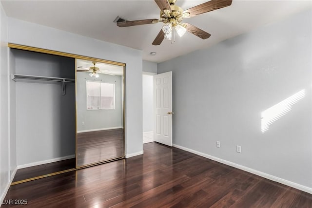 unfurnished bedroom with dark wood-type flooring, a closet, and ceiling fan