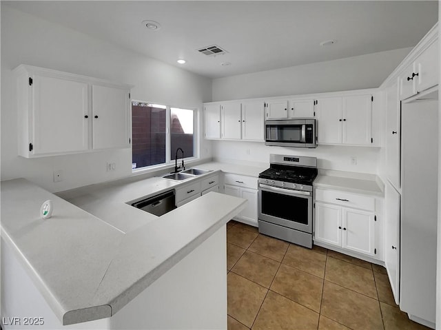 kitchen featuring white cabinetry, kitchen peninsula, stainless steel appliances, sink, and light tile patterned flooring