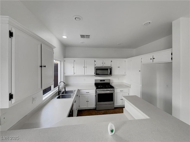 kitchen with white cabinetry, appliances with stainless steel finishes, sink, and dark tile patterned floors