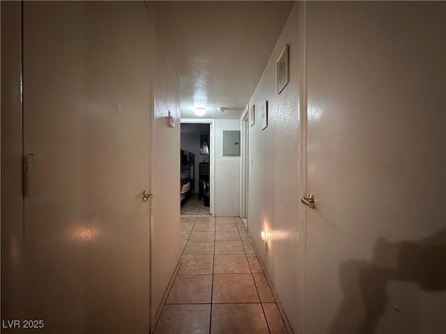 hall with electric panel, a textured ceiling, and light tile patterned floors