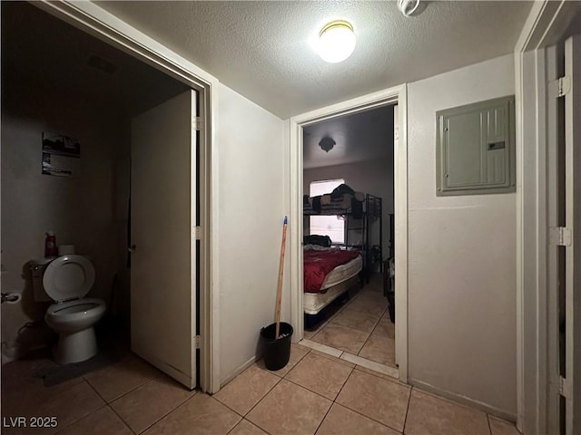 hall featuring light tile patterned floors, electric panel, and a textured ceiling