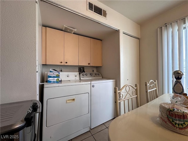 laundry room featuring cabinets, washer and dryer, and light tile patterned floors