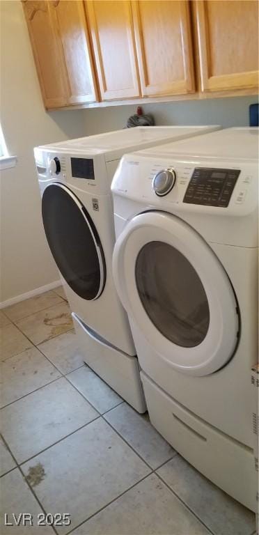 laundry room featuring cabinets, light tile patterned floors, and washing machine and clothes dryer