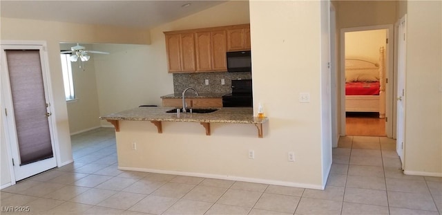 kitchen with a kitchen bar, sink, kitchen peninsula, decorative backsplash, and black appliances