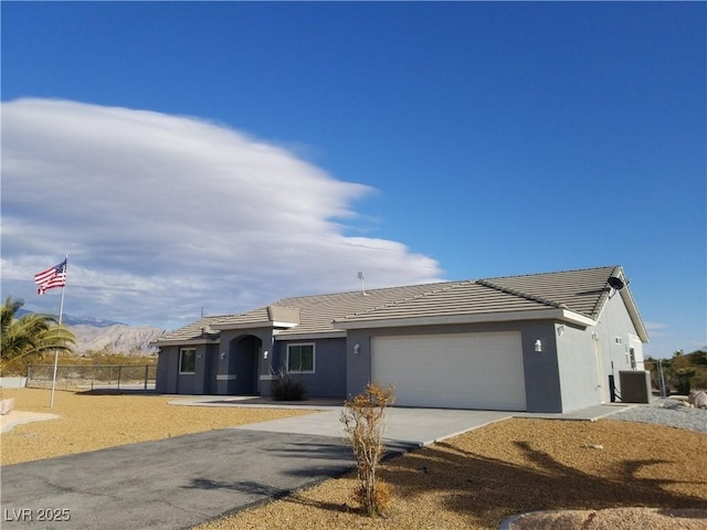 single story home with a garage, a mountain view, and central air condition unit