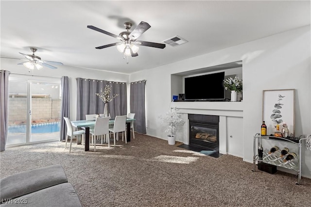 living room featuring a tiled fireplace, carpet, and ceiling fan