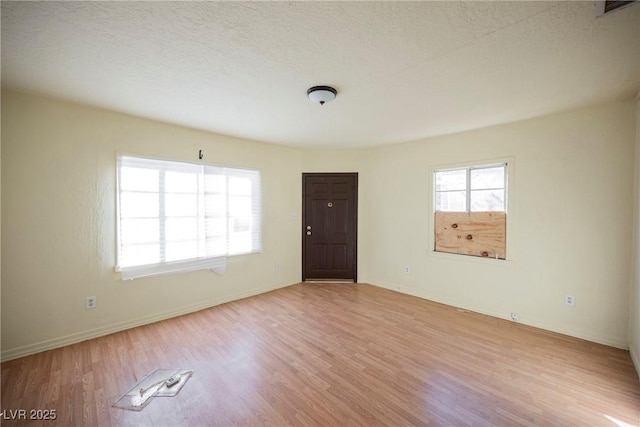 unfurnished room featuring a wealth of natural light, a textured ceiling, and light wood-type flooring