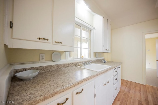 kitchen with light hardwood / wood-style floors, sink, and white cabinets