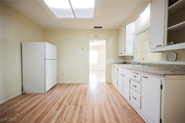 kitchen with white refrigerator, sink, light hardwood / wood-style flooring, and white cabinets