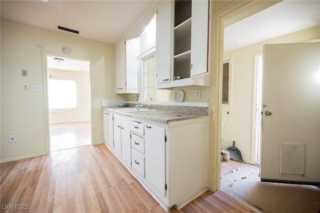 kitchen featuring white cabinetry, sink, and light wood-type flooring