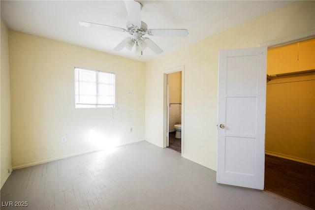 unfurnished bedroom with a walk in closet, ensuite bath, a closet, ceiling fan, and hardwood / wood-style floors