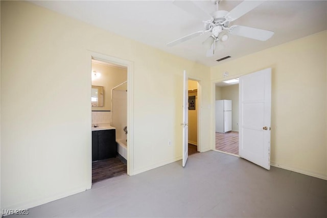 unfurnished bedroom featuring ensuite bath, ceiling fan, and white refrigerator