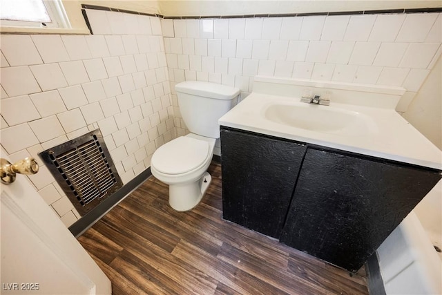 bathroom with vanity, toilet, wood-type flooring, and tile walls