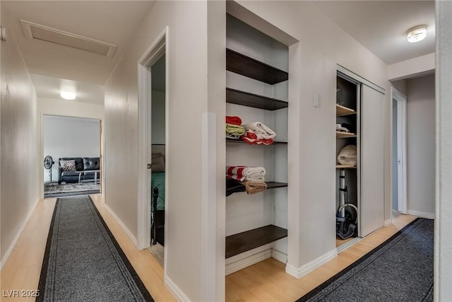 hall featuring built in shelves and light wood-type flooring