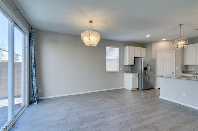 kitchen featuring hanging light fixtures, white cabinetry, and stainless steel fridge