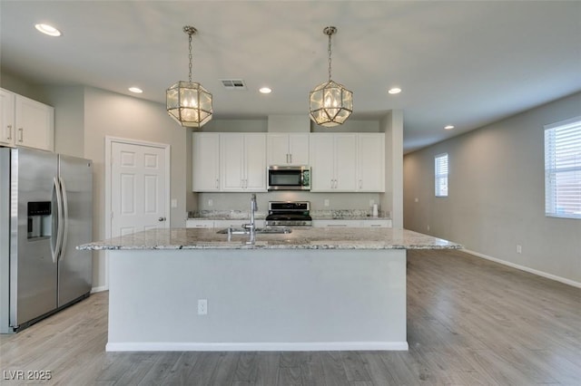 kitchen featuring stainless steel appliances, white cabinetry, pendant lighting, and a center island with sink