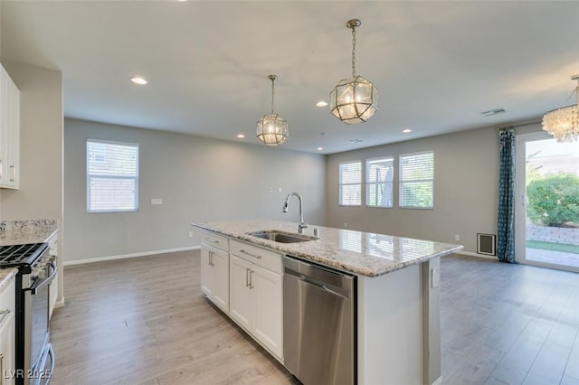 kitchen with pendant lighting, sink, appliances with stainless steel finishes, white cabinetry, and an island with sink