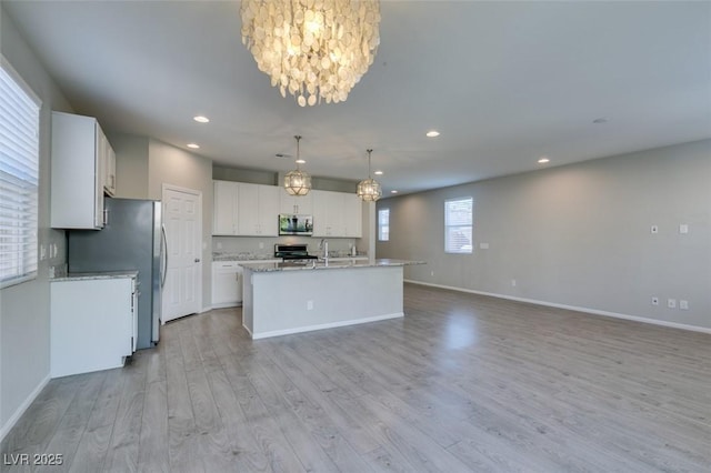 kitchen featuring white cabinetry, appliances with stainless steel finishes, a center island with sink, and pendant lighting