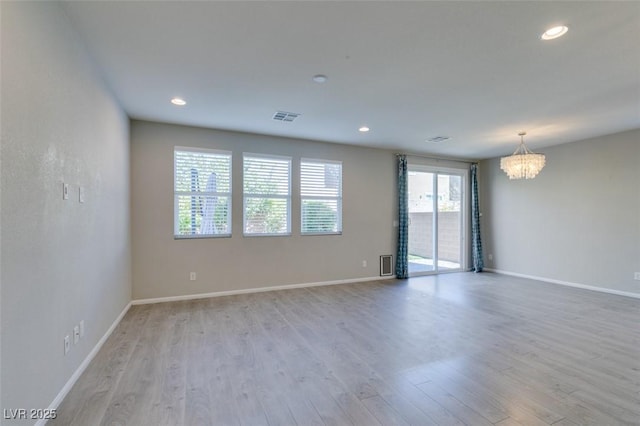 unfurnished room featuring a notable chandelier and light hardwood / wood-style flooring