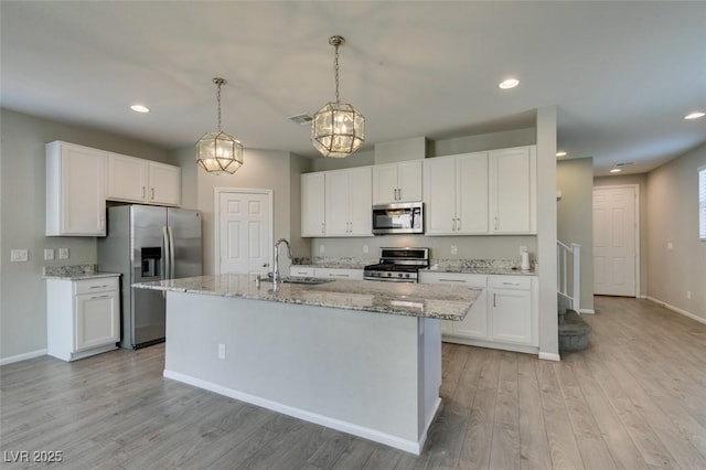 kitchen featuring an island with sink, appliances with stainless steel finishes, sink, and white cabinets