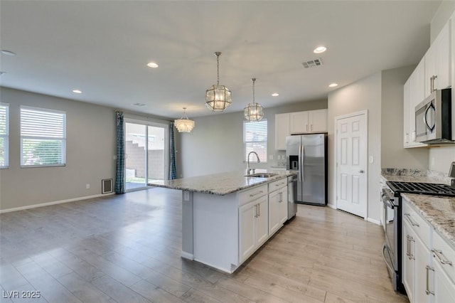 kitchen featuring sink, white cabinetry, hanging light fixtures, stainless steel appliances, and an island with sink