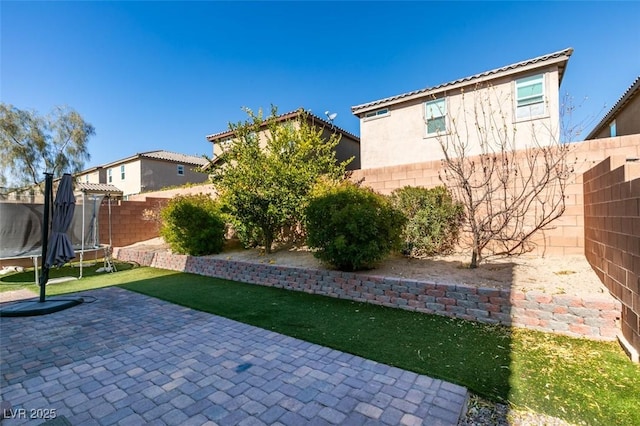 view of yard with a trampoline and a patio