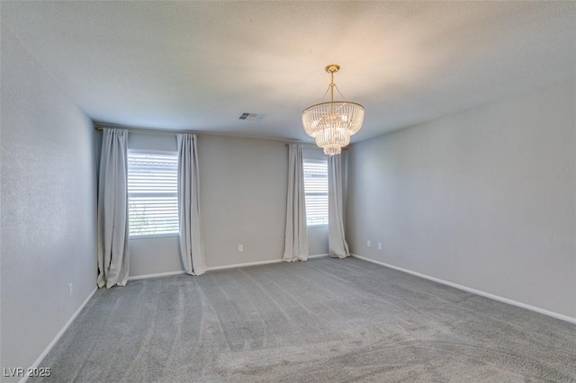 carpeted empty room with an inviting chandelier and a wealth of natural light