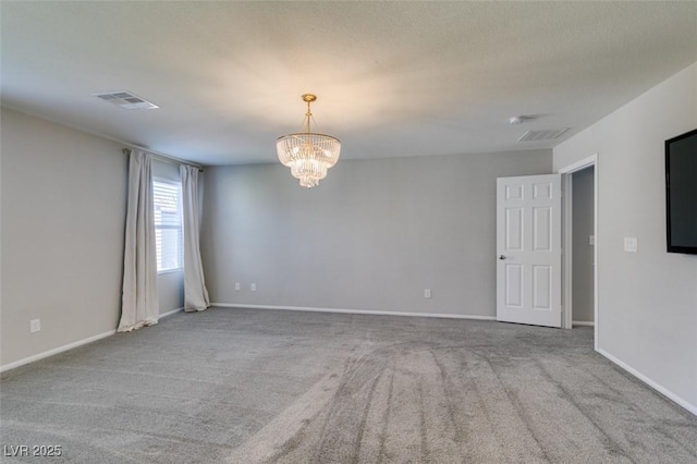 carpeted empty room featuring a notable chandelier