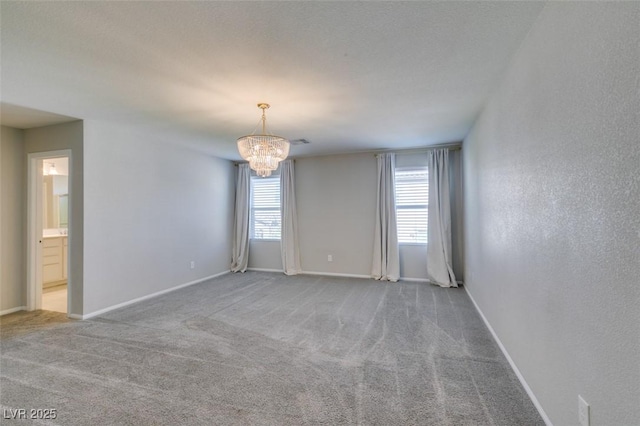 carpeted spare room with a healthy amount of sunlight and a chandelier