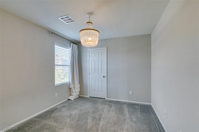 carpeted spare room featuring an inviting chandelier