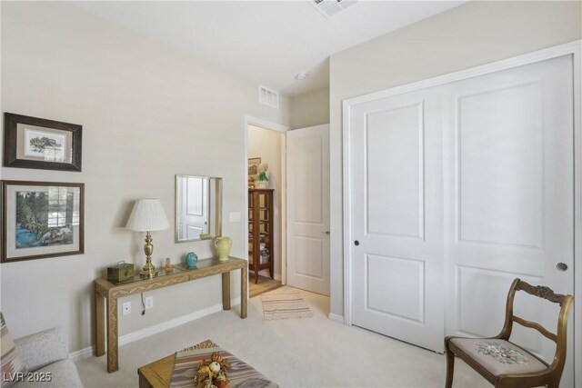 living area featuring visible vents, light carpet, and baseboards