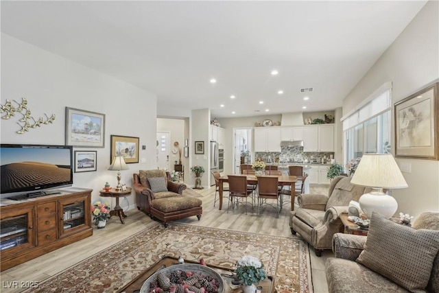 living area with baseboards, recessed lighting, visible vents, and light wood-type flooring